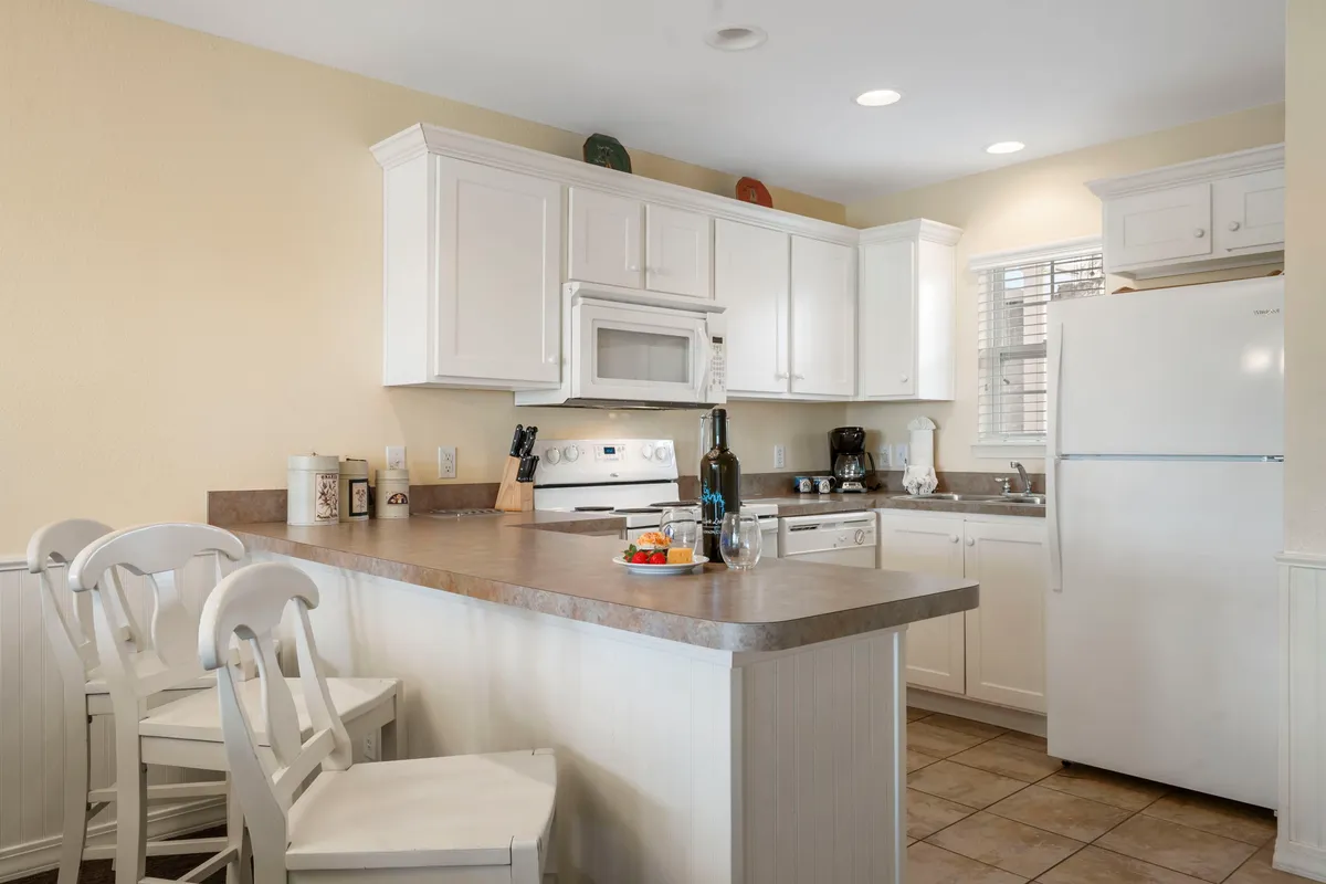 A welcoming kitchen with a central island, clean white cabinetry, and stylish countertop decor. The space is set up for cooking and casual dining, inviting culinary creativity and connection.