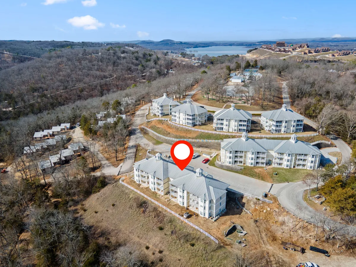 A peaceful exterior shot of a cluster of resort buildings set against a backdrop of trees and Table Rock Lake. The image suggests easy access to water, scenic walks, and opportunities for outdoor recreation.