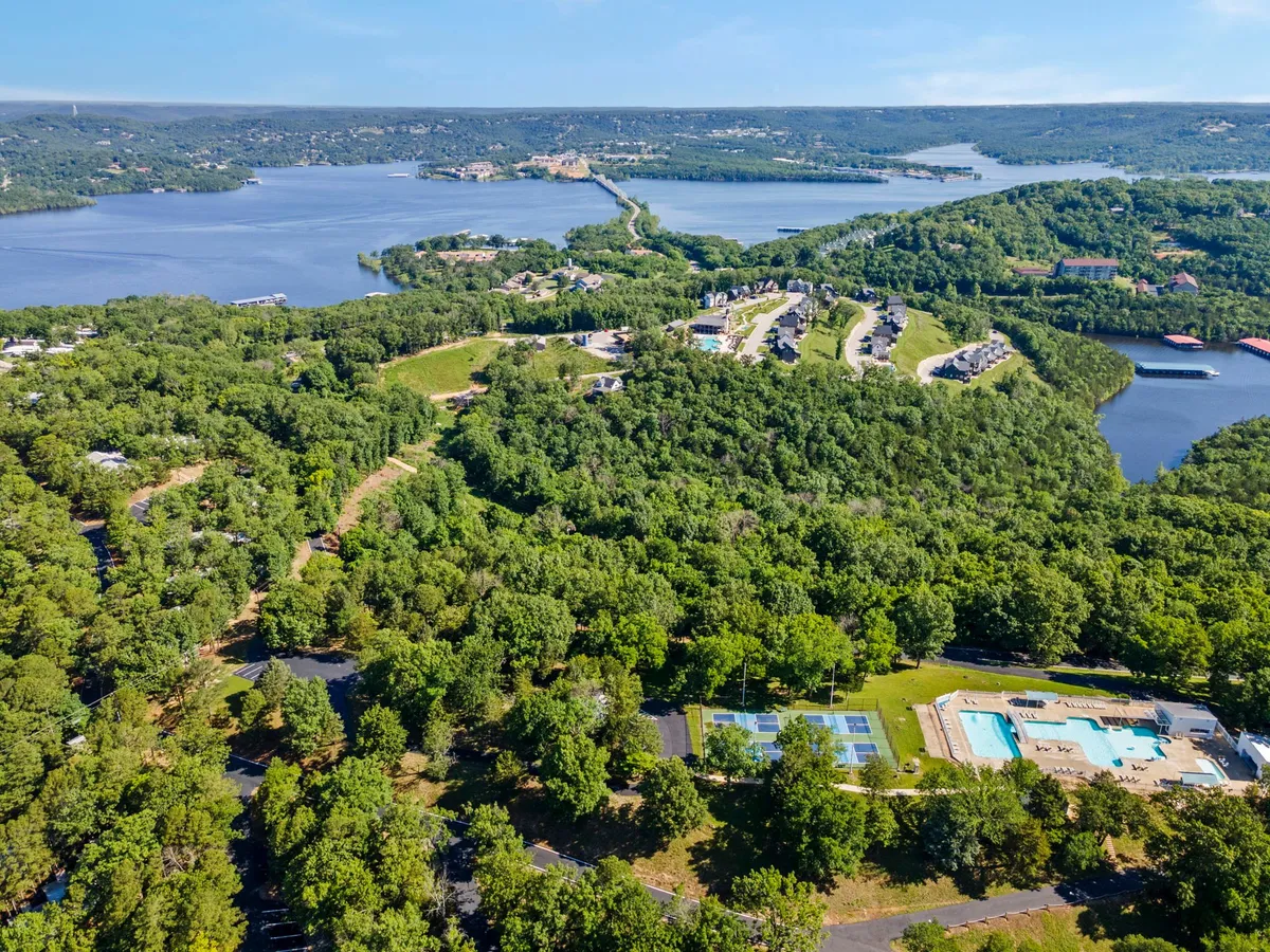 A tranquil view of lush greenery, sparkling water, and recreational areas within a residential community. Walking trails and open spaces connect the homes to the lakeshore, suggesting ample opportunities for outdoor exploration.